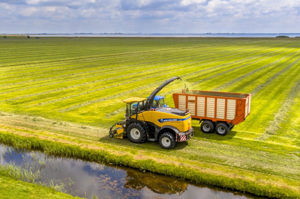 Tractors on fresh mowed green agricultural grassland